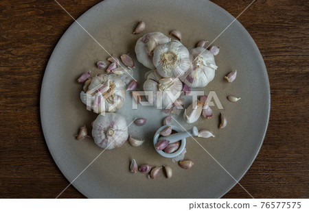 Garlic bulbs and Garlic cloves in Ceramic plate on Wooden rustic table. 76577575