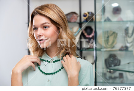 Woman choosing greenstone beads 76577577