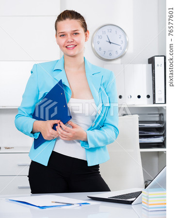 Businesswoman is standing with documents 76577601
