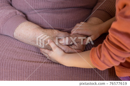 close-up of the hands of an elderly old woman and a little girl. old age and youth 76577619