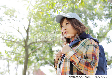 陽光透過樹梢，一位女士正在爬山 76577725