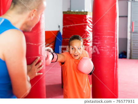 Girl with boxing gloves posing in defended stance 76577931