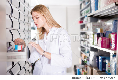 Young female customer searching for reliable body care products in pharmacy 76577967