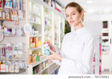 Young friendly pharmacist offering reliable medicine in pharmacy 76578061