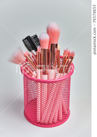 basket with beautiful pink cosmetic brushes on white background 76578655
