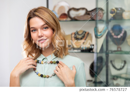 Girl trying on natural stones necklace Girl trying on natural stones necklace 76578727