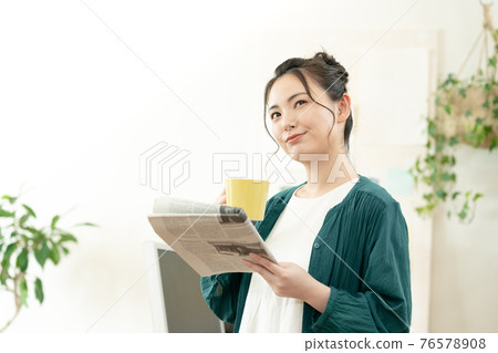 A woman reading an English newspaper A woman reading an English newspaper 76578908
