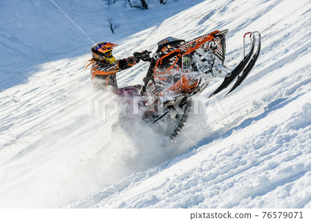 Athlete on a snowmobile moving in the mountains 76579071