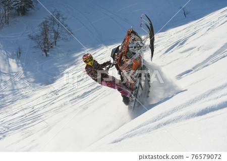 Athlete on a snowmobile moving in the mountains 76579072