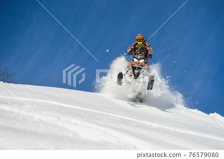 Athlete on a snowmobile moving in the mountains Athlete on a snowmobile moving in the mountains 76579080