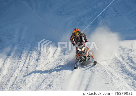 Athlete on a snowmobile moving in the mountains Athlete on a snowmobile moving in the mountains 76579081