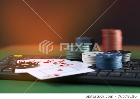 Online gaming platform, casino and gambling business. Cards, dice and multi-colored game pieces on laptop keyboard Online gaming platform, casino and gambling business. Cards, dice and multi-colored game pieces on laptop keyboard 76579180