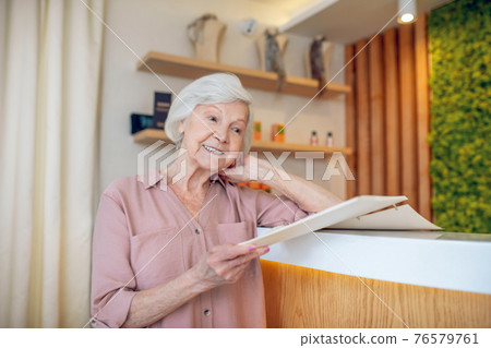 Gray-haired woman standing near reception in a spa center Gray-haired woman standing near reception in a spa center 76579761