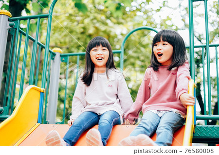 Two girls having fun playing in the park Two girls having fun playing in the park 76580008