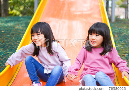 Two girls having fun playing in the park Two girls having fun playing in the park 76580023