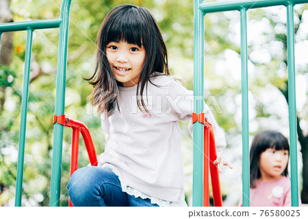 Two girls having fun playing in the park Two girls having fun playing in the park 76580025