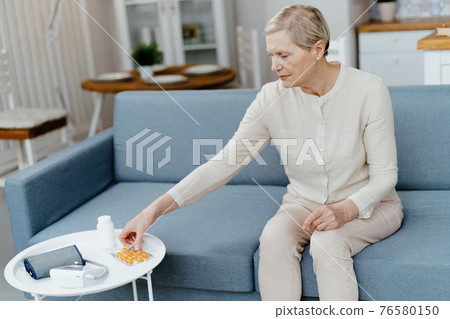 mature woman taking a pill out of the package . 76580150