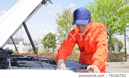 A male auto mechanic who opens the hood of a car 76580792