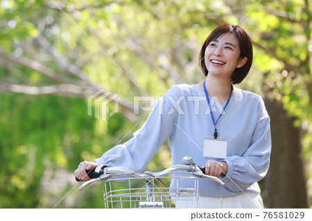 A woman walking by pushing a bicycle A woman walking by pushing a bicycle 76581029