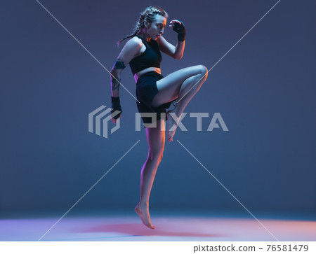 Caucasian female MMA fighter training isolated on blue background in neon light 76581479