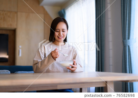 Young woman eating yogurt Young woman eating yogurt 76582698