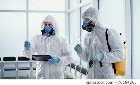 team of professional disinfector making a record of the work done . 76584265