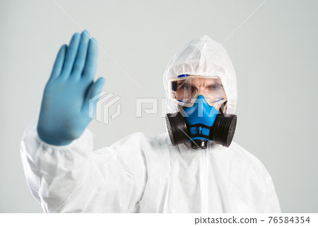 man in a biohazard suit makes a stop sign. man in a biohazard suit makes a stop sign. 76584354