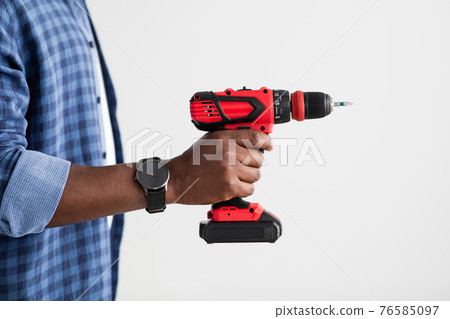 Home renovation, electric tool. Black man with smart watch holding electric drill, standing over white background 76585097