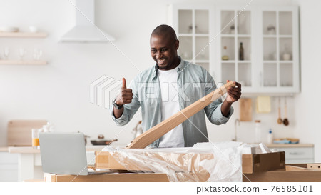 Happy black blogger gesturing thumb up, making table while shooting video instructions for assembling furniture at home Happy black blogger gesturing thumb up, making table while shooting video instructions for assembling furniture at home 76585101