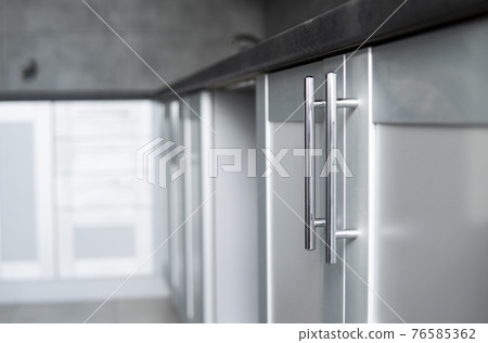 Modern minimalism style kitchen interior in monochrome tones. Custom kitchen with grey white facadesmdf and dark grey countertop with installed kitchen hood and sink. Modular kitchen from chipboard. 76585362