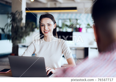 Male and female colleagues working at the table in office 76587717