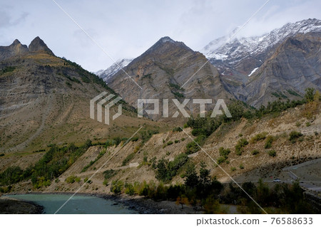 A small car is moving along a serpentine path between the Himalayan Mountains. Small against a huge background. A small car is moving along a serpentine path between the Himalayan Mountains. Small against a huge background. 76588633