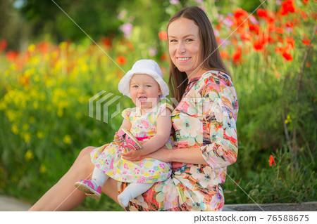 Happy woman and child on the poppy meadow. 76588675