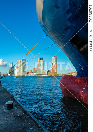 View of Rotterdam skyscrapers skyline from under cargo vessel moored to the quay of Nieuwe Maas river View of Rotterdam skyscrapers skyline from under cargo vessel moored to the quay of Nieuwe Maas river 76588701
