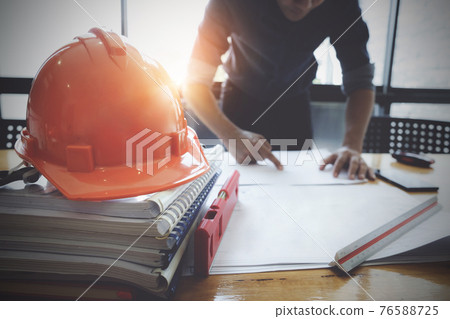 Interior Architect with blueprint for architectural plan, engineer sketching a construction project concept in engineer office. 76588725