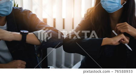 Business or accountant wear mask and bumping elbows for keeping social distance instead of hugs or handshake at morning in home office. Business or accountant wear mask and bumping elbows for keeping social distance instead of hugs or handshake at morning in home office. 76588933