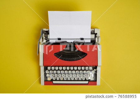 Top view of red vintage typewriter with white blank paper sheet 76588955