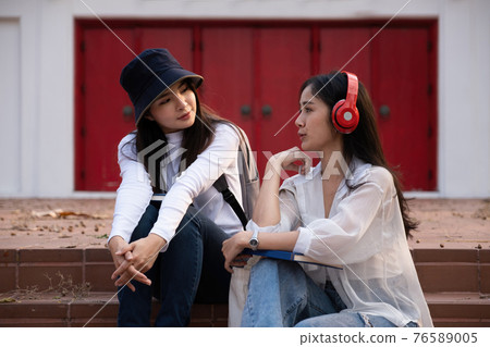 Asian woman traveler with backpack talking about history this place and sitting in stair, travel holiday relaxation concept. 76589005