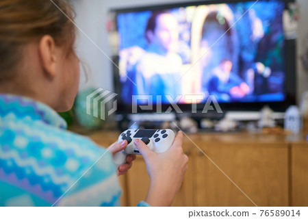 Girl playing video game with joystick at home Girl playing video game with joystick at home 76589014