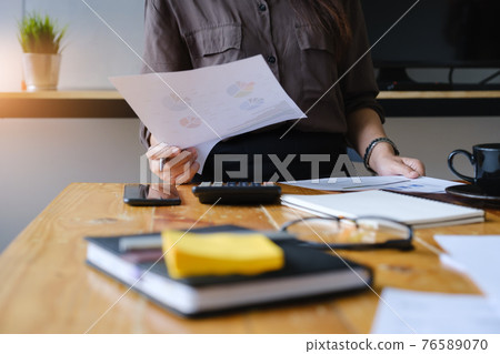 Close up Hand of Businesswoman pointing and analyzing charts by document. 76589070