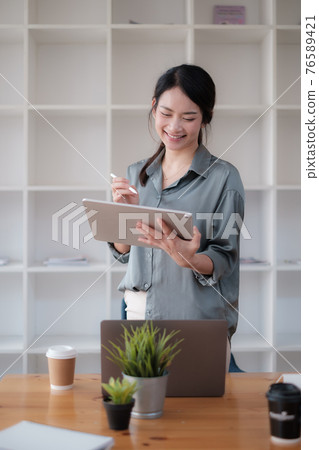 Portrait of Asian Business woman working with tablet in office. Work from home concept. Portrait of Asian Business woman working with tablet in office. Work from home concept. 76589421