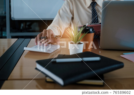 Young accountant man analyzes financial data using calculator and laptop computer to compute and summarize big data for present on video conference. financial concept. Young accountant man analyzes financial data using calculator and laptop computer to compute and summarize big data for present on video conference. financial concept. 76589602