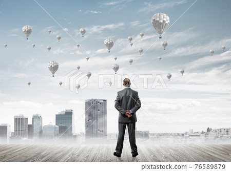 Motivation and inspiration concept with modern cityscape and businessman observing it 76589879