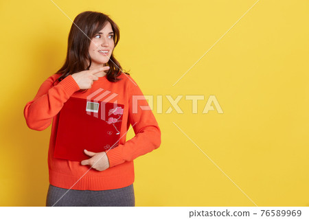Young smiling woman holding floor scale and pointing aside with index finger, good looking lady showing something at blank space, girl with dark hair demonstrating ad, Young smiling woman holding floor scale and pointing aside with index finger, good looking lady showing something at blank space, girl with dark hair demonstrating ad, 76589969