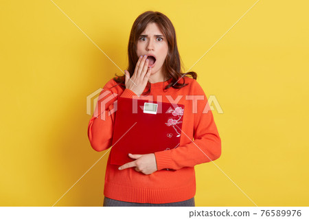 Frustrated woman with scale in hands posing isolated over yellow background, female being very shocked, cover opened mouth with palm, needs to keep fit and loosing weight. Frustrated woman with scale in hands posing isolated over yellow background, female being very shocked, cover opened mouth with palm, needs to keep fit and loosing weight. 76589976