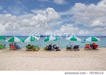 Row of beach umbrella parasols with wooden beach chairs on tropical sandy beach in sunny day at Koh Nang Yuan Island 76590218