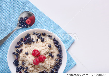 Image of healthy breakfast, plate with oatmeal and berries and spoon, raspberries and blueberries with porridge. Healthy eating and diet concept. Healthy breakfast for family. Copy space fpr promotion Image of healthy breakfast, plate with oatmeal and berries and spoon, raspberries and blueberries with porridge. Healthy eating and diet concept. Healthy breakfast for family. Copy space fpr promotion 76590686