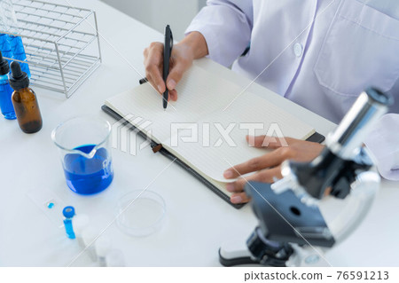 scientists researching in laboratory in white lab coat, gloves analysing, looking at test tubes sample, biotechnology concept 76591213