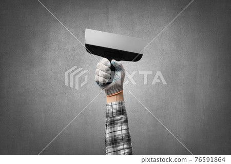 hand holds a construction tool - stainless spatula hand holds a construction tool - stainless spatula 76591864