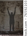 Shadow of a man with raised hands. 76592103